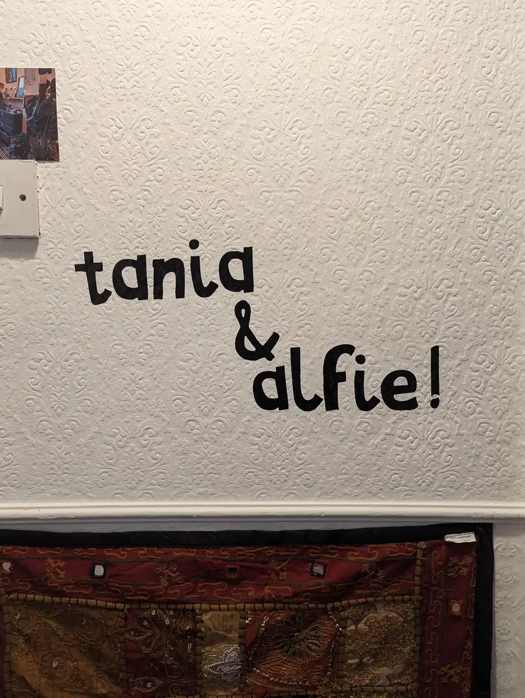 picture of a vinyl sign stuck to a wall that says "tania & alfie!"